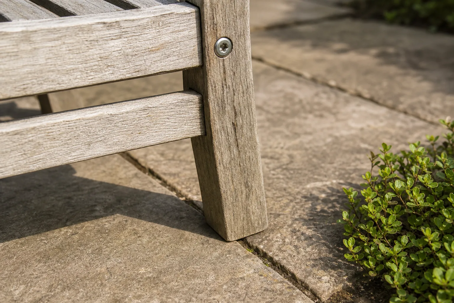 A tightened screw and level foot keep a weathered wooden garden chair steady on an existing stone paver.
