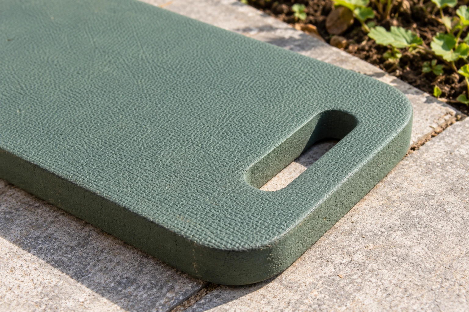 A textured foam kneeling pad corner resting on ordinary paving