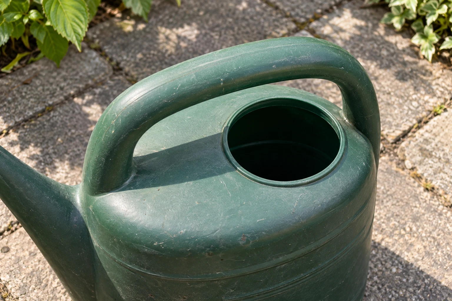 Close-up of a watering can's handle and filling opening.