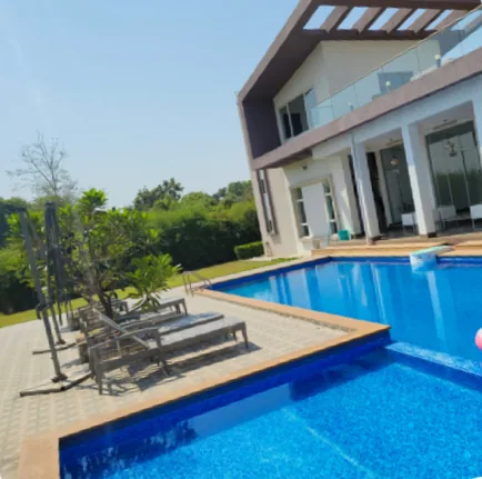 The original phone photo of the backyard: bare grass, a leafless tree and sun loungers on plain paving beside the pool